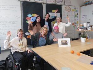 Die Bildungsfachkräfte winken lachend in die Kamera.